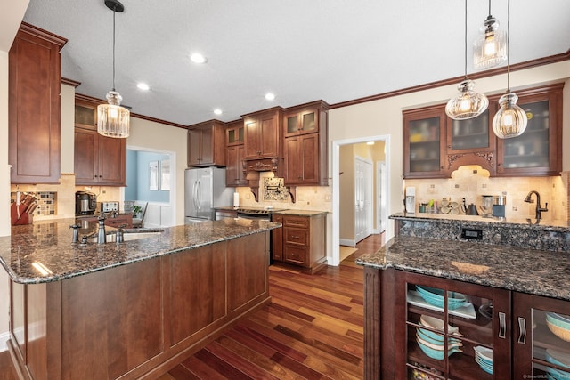 kitchen with dark wood-type flooring, sink, decorative light fixtures, dark stone countertops, and stainless steel appliances