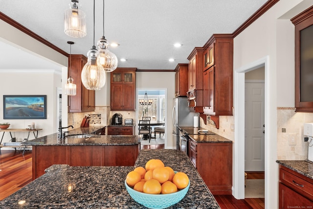 kitchen featuring sink, dark stone counters, hanging light fixtures, a center island, and dark wood-type flooring