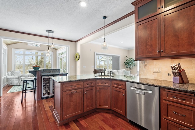 kitchen with decorative light fixtures, stainless steel dishwasher, dark stone counters, and kitchen peninsula