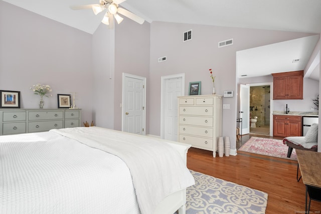 bedroom featuring ceiling fan, lofted ceiling, connected bathroom, and light hardwood / wood-style floors