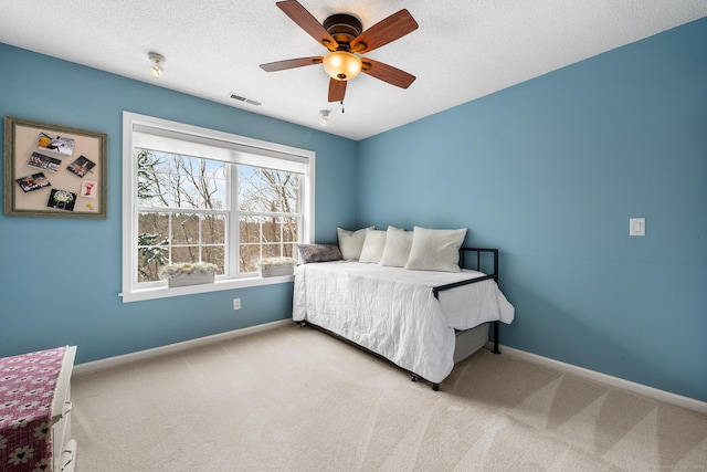 carpeted bedroom with ceiling fan and a textured ceiling