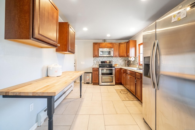 kitchen featuring tasteful backsplash, light tile patterned floors, wooden counters, and appliances with stainless steel finishes