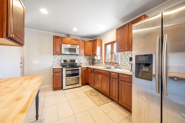 kitchen with tasteful backsplash, stainless steel appliances, sink, and butcher block countertops