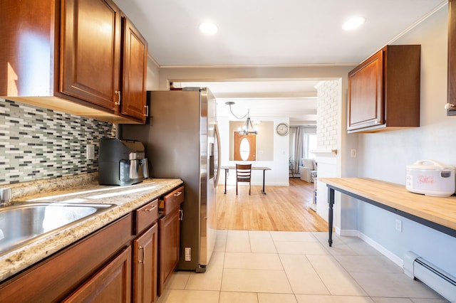 kitchen with butcher block countertops, a baseboard heating unit, backsplash, hanging light fixtures, and light tile patterned flooring