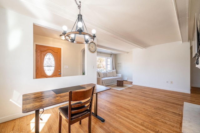 dining space with an inviting chandelier, beamed ceiling, and light wood-type flooring