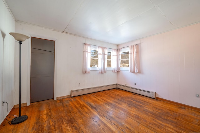 unfurnished bedroom featuring dark hardwood / wood-style flooring and a baseboard heating unit