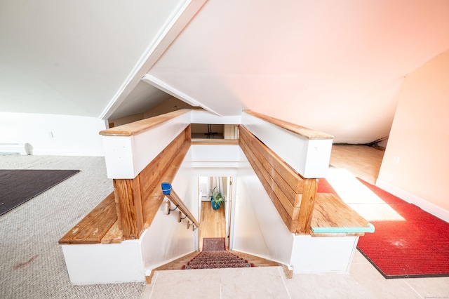 stairs with a baseboard heating unit, vaulted ceiling, and carpet