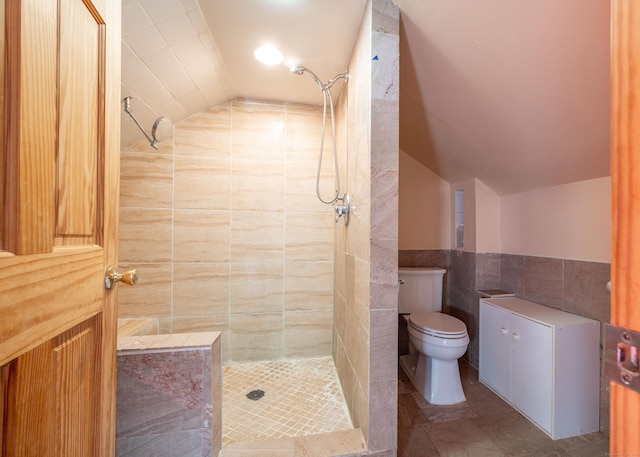 bathroom featuring vaulted ceiling, tiled shower, tile walls, and toilet