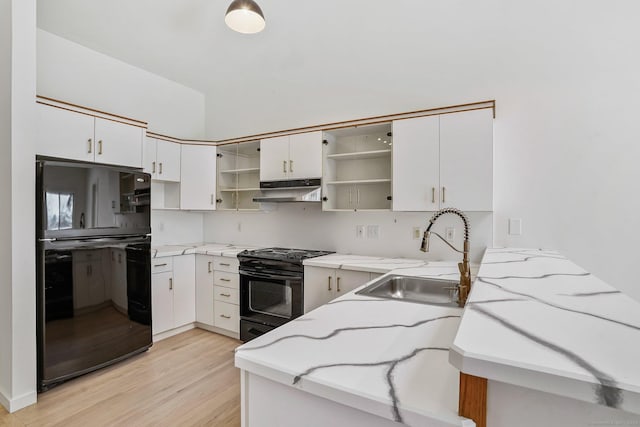 kitchen featuring open shelves, light stone countertops, under cabinet range hood, black appliances, and a sink