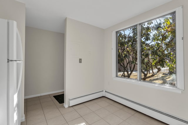 unfurnished room with a baseboard heating unit, a wealth of natural light, and light tile patterned flooring