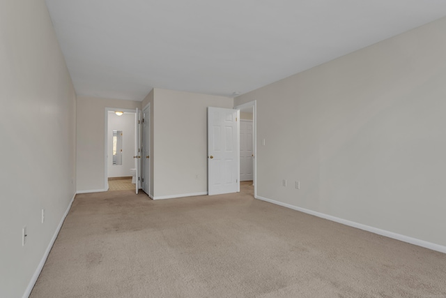 unfurnished bedroom featuring light colored carpet, connected bathroom, and a walk in closet