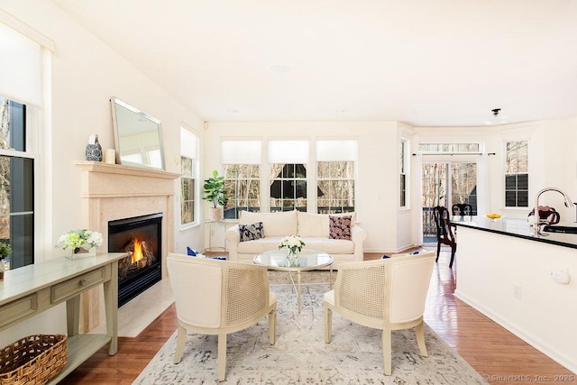 living room with sink, a high end fireplace, and light hardwood / wood-style flooring