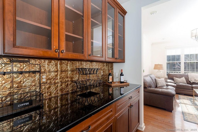 bar featuring dark stone countertops, light wood-type flooring, and decorative backsplash