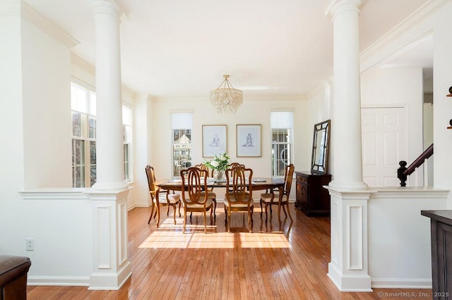 dining area with hardwood / wood-style floors, ornamental molding, and ornate columns