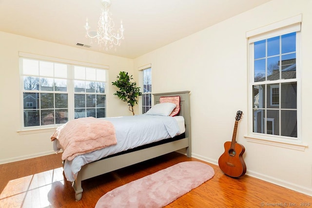 bedroom with an inviting chandelier and wood-type flooring