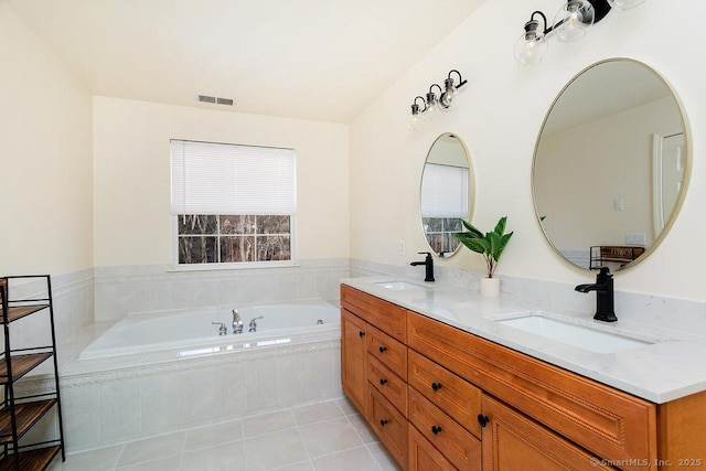 bathroom with tile patterned flooring, vanity, and tiled bath