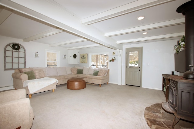 living room featuring carpet floors, a wood stove, beam ceiling, and baseboard heating