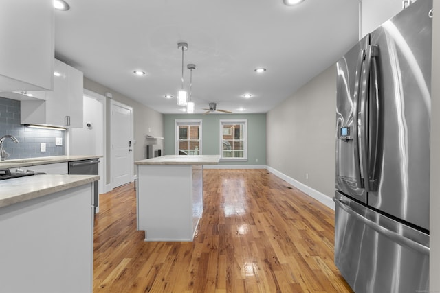 kitchen featuring white cabinetry, tasteful backsplash, stainless steel fridge with ice dispenser, light wood-type flooring, and pendant lighting