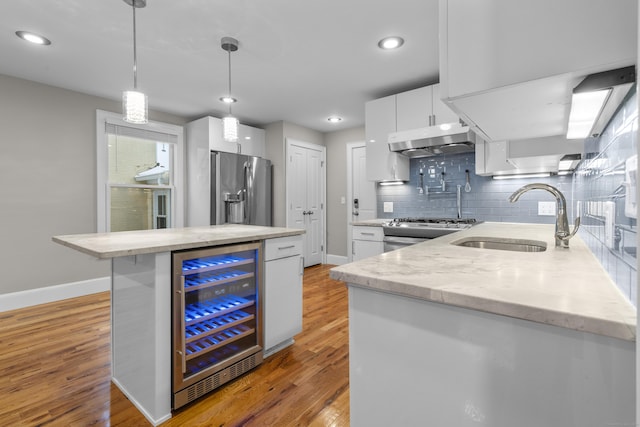 kitchen featuring sink, white cabinetry, hanging light fixtures, stainless steel appliances, and beverage cooler