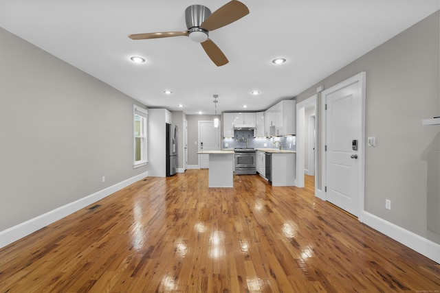 kitchen featuring appliances with stainless steel finishes, white cabinetry, hanging light fixtures, ceiling fan, and light wood-type flooring