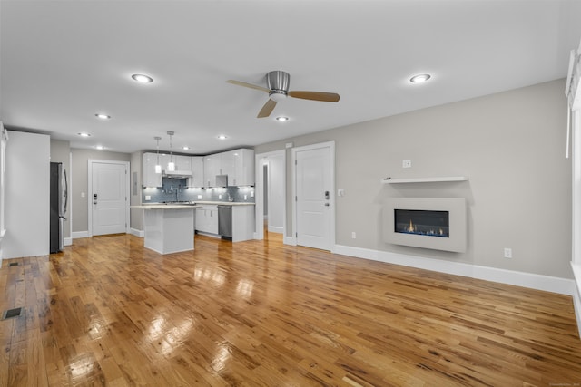 unfurnished living room featuring ceiling fan and light wood-type flooring