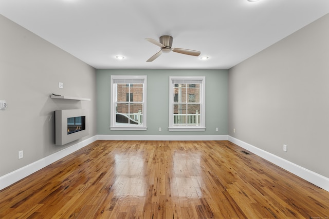 unfurnished living room with ceiling fan and wood-type flooring