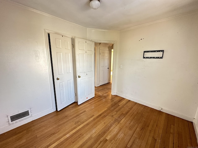 unfurnished bedroom with crown molding, a closet, and light wood-type flooring