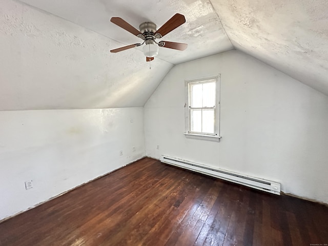 additional living space with a baseboard radiator, dark hardwood / wood-style flooring, vaulted ceiling, and a textured ceiling