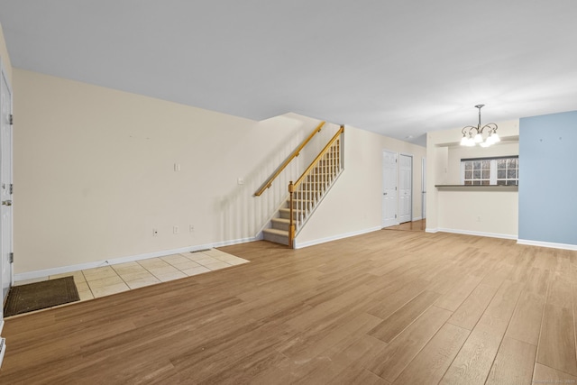 unfurnished living room with an inviting chandelier and light hardwood / wood-style flooring