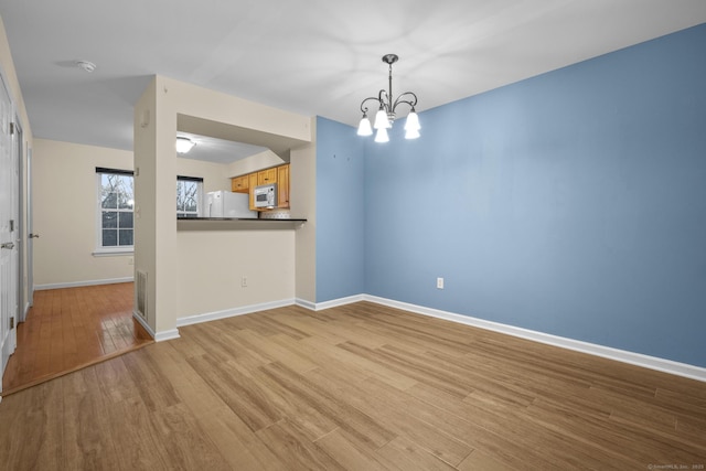 unfurnished dining area featuring a notable chandelier and light hardwood / wood-style floors