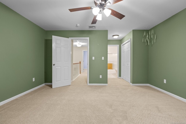 unfurnished bedroom with light colored carpet, a closet, ceiling fan, and ensuite bathroom