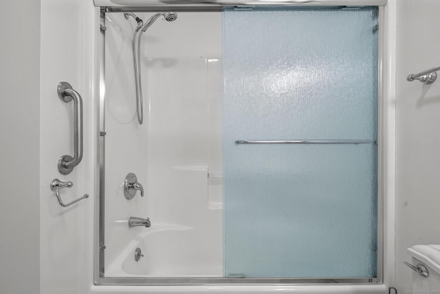 bathroom with toilet and combined bath / shower with glass door