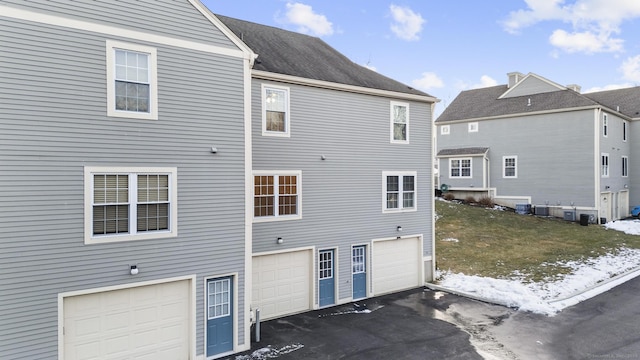 back of property featuring a garage and central AC unit