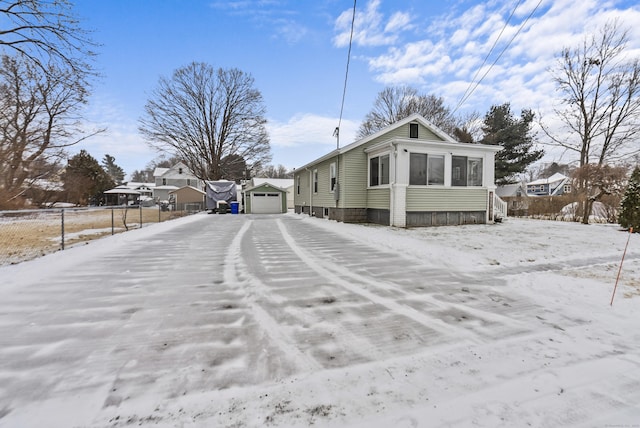 snow covered property with a garage and an outdoor structure