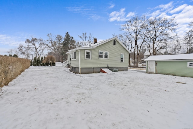 snow covered back of property with an outbuilding and a garage