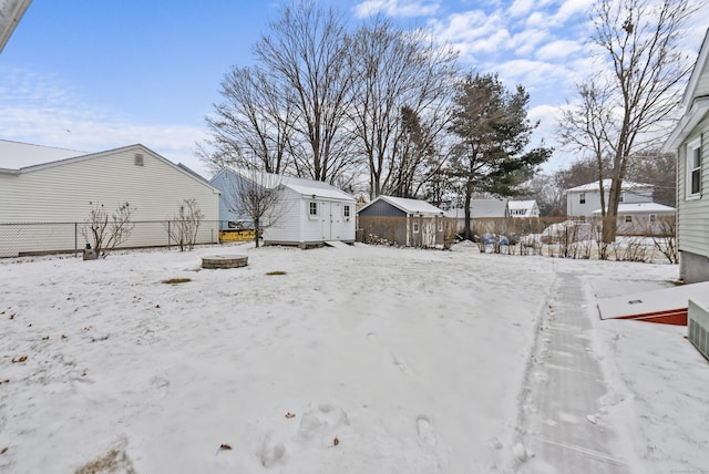 snowy yard featuring a storage unit and an outdoor fire pit