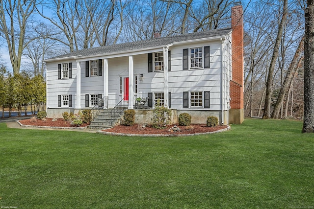 split foyer home featuring a front lawn and a chimney