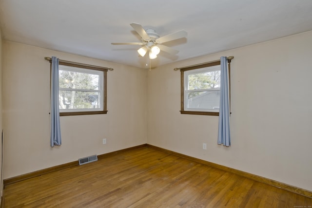 empty room with hardwood / wood-style flooring, plenty of natural light, and ceiling fan