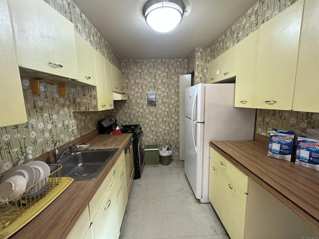 kitchen with butcher block counters, sink, cream cabinetry, and range