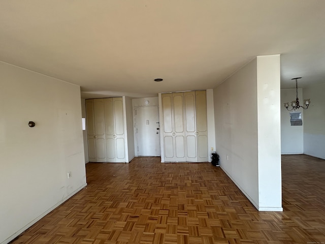 hall featuring dark parquet floors and a notable chandelier