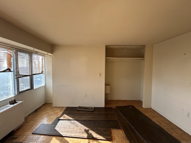 unfurnished bedroom featuring light parquet floors and a closet