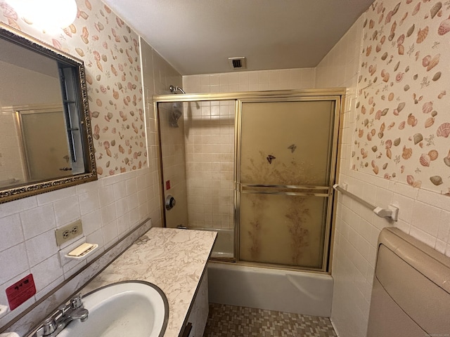 full bathroom featuring vanity, tile walls, shower / bath combination with glass door, and toilet