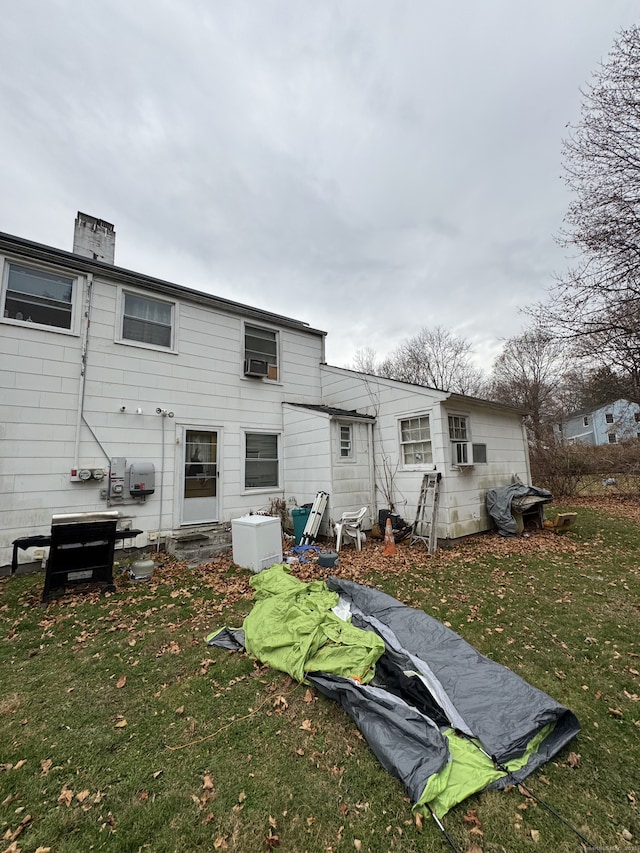 rear view of house featuring cooling unit and a yard