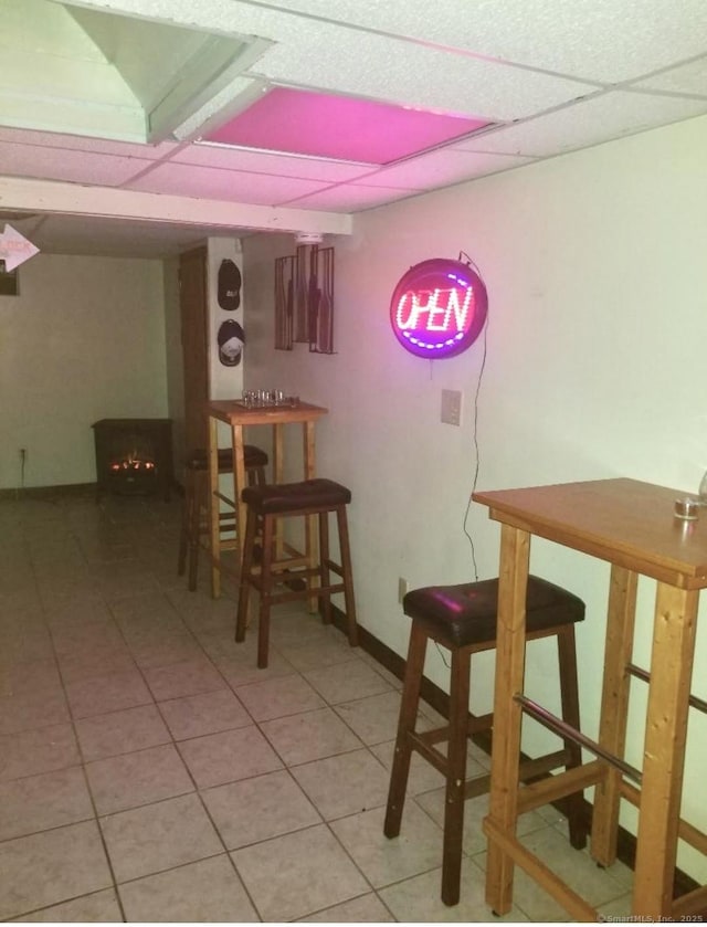 bar featuring a paneled ceiling and light tile patterned flooring