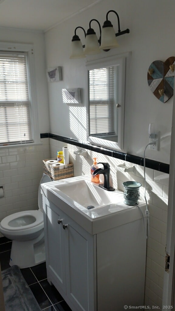 bathroom featuring vanity, toilet, tile patterned flooring, and tile walls