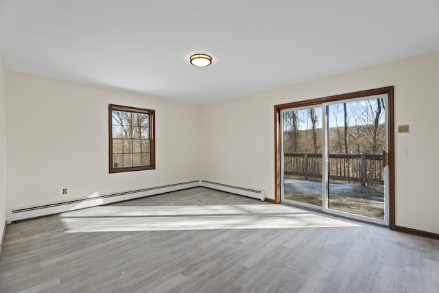 unfurnished room featuring plenty of natural light, baseboard heating, and light hardwood / wood-style flooring