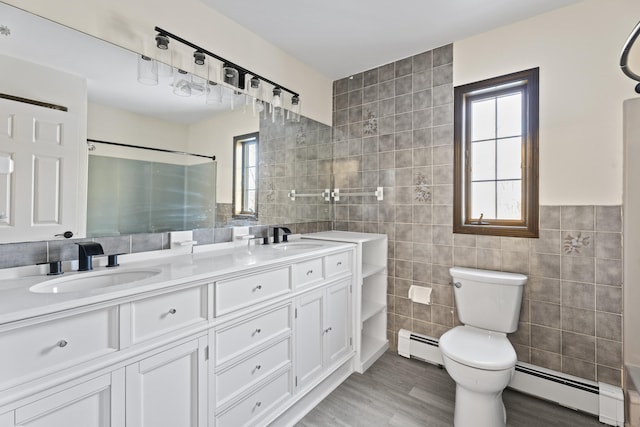 bathroom with vanity, wood-type flooring, tile walls, and a baseboard heating unit