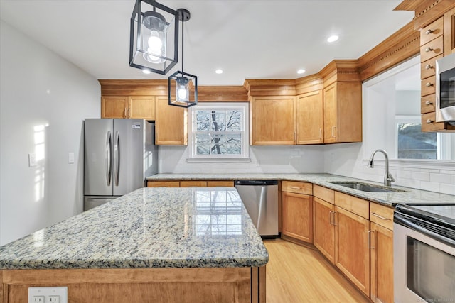 kitchen featuring stainless steel appliances, decorative light fixtures, sink, and a kitchen island