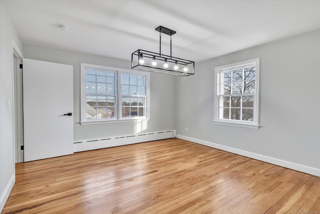 unfurnished dining area featuring light hardwood / wood-style flooring, a baseboard radiator, and rail lighting