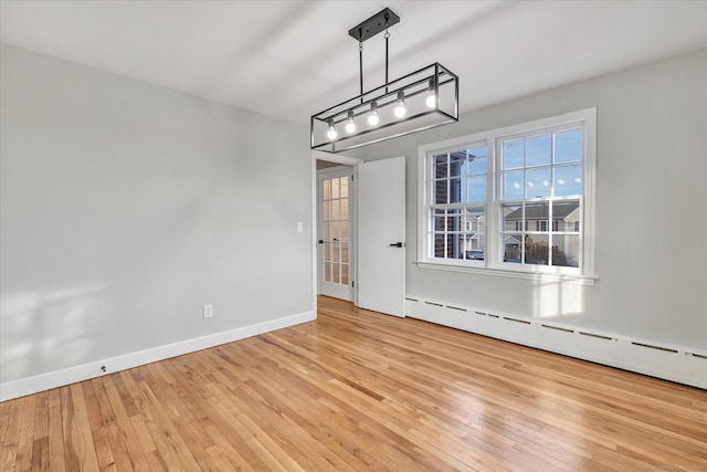 unfurnished dining area with light wood-type flooring and a baseboard heating unit